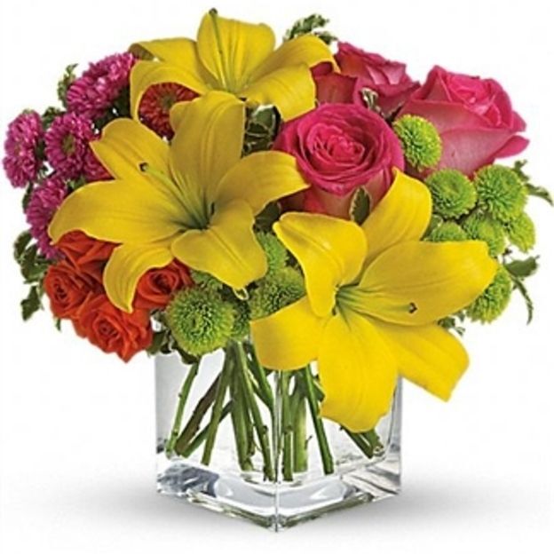 Lilies, roses, carnations, daisies, solidago, and greens arranged in a clear glass vase—mixed colors, balanced shape, and easy to place.